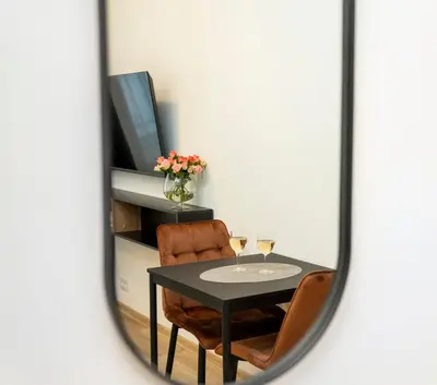 a mirror reflecting a table with two glasses of wine at Central Station Apartment No3 in Kaunas