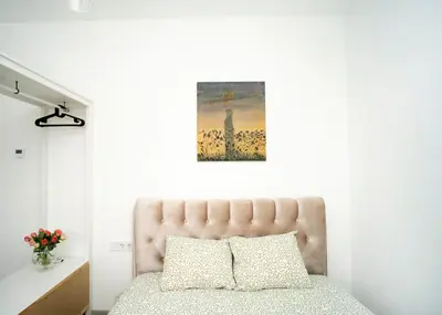 a bedroom with a bed and a painting on the wall at Central Station Apartment No6 in Kaunas