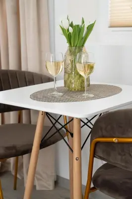 two glasses of wine on a table with a vase of flowers at Central Station Apartment No6 in Kaunas