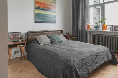 a bedroom with a bed and a table and a painting at Apt-Gallery in Central Kaunas in Kaunas