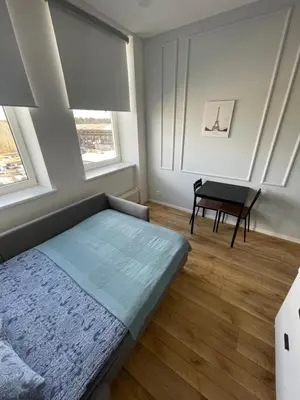 a bedroom with a bed and a table and two windows at 25 Airport Apartment in Vilnius
