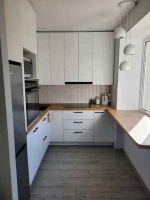 a kitchen with white cabinets and a wooden floor at Maironio apartamentai in Radviliškis