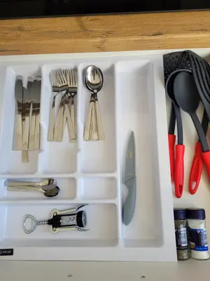 a white drawer filled with utensils on a table at Maironio apartamentai in Radviliškis
