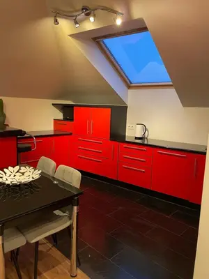 a kitchen with red cabinets and a large skylight at Apartamentai prie Seimo in Vilnius