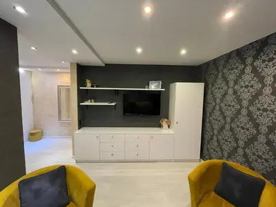 a living room with two yellow chairs and a television at Apartment in Šiauliai in Šiauliai