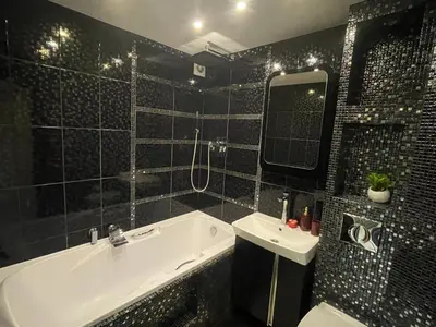 a black tiled bathroom with a tub and a sink at Apartment in Šiauliai in Šiauliai