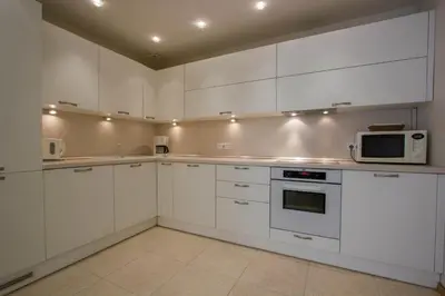 a white kitchen with white cabinets and a microwave at Historic Central Apartment in Vilnius