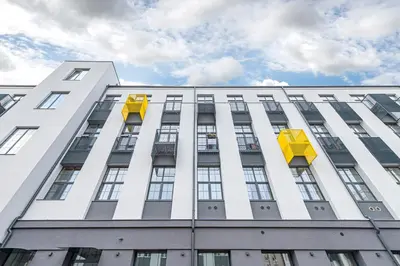 a tall white building with yellow boxes on it at Modern loft apartment near Christ's Resurrection Church by Polo apartments in Kaunas
