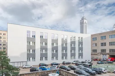 a large white building with cars parked in a parking lot at Modern loft apartment near Christ's Resurrection Church by Polo apartments in Kaunas