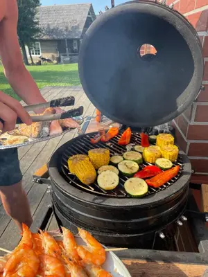 a man is cooking food on a grill at Barškulių Sodyba in Ricieliai