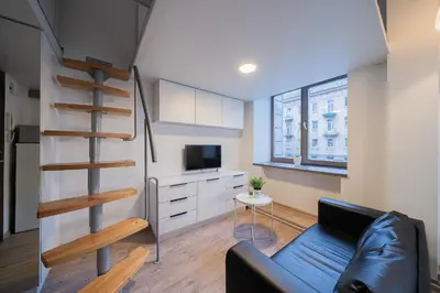 a living room with a staircase and a couch at Kauno Mini Loft by Lollo Stay in Vilnius