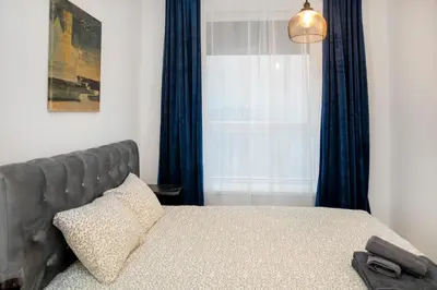 a bedroom with a bed with blue curtains and a window at Central Station Apartment No4 in Kaunas