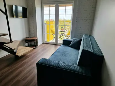 a living room with a couch and a balcony at Radio city loft-468 in Kaunas