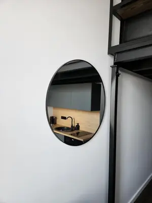 a round mirror on the wall of a bathroom at Radio city loft-468 in Kaunas