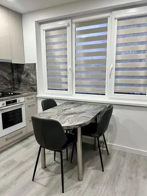 a kitchen with a table and chairs and windows at Marijos apartamentai in Birštonas