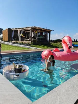 a woman in a pool with two inflatable flamingos at Poilsiaviete Vakaris in Gudeliai