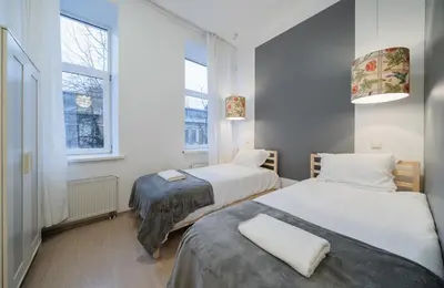 two beds in a small room with two windows at Halės Self Check-in Guest House - Lollo Stay in Vilnius