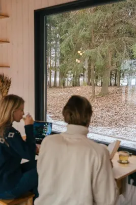 two people sitting at a table looking out a window at Living art piece at the lake. in Užutrakis