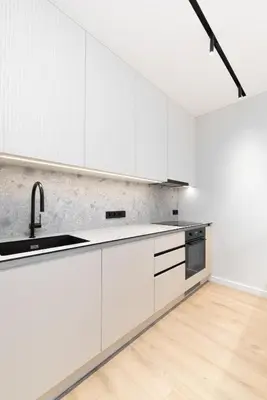 a kitchen with white cabinets and a sink at Hygge Sand Apartment in Vilnius