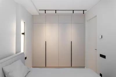 a bedroom with white cabinets and a bed at Hygge Sand Apartment in Vilnius