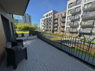 a balcony with chairs and a fence and buildings at Hygge Sand Apartment in Vilnius