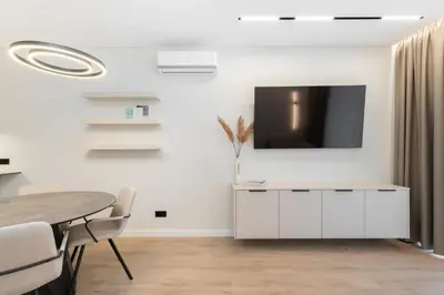 a dining room with a tv on a white wall at Hygge Sand Apartment in Vilnius