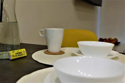 a table with two white cups and plates on it at Nauji apartamentai su kiemeliu in Kaunas