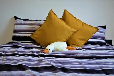 a stuffed duck laying on a bed with pillows at Nauji apartamentai su kiemeliu in Kaunas
