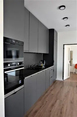 a kitchen with black and white appliances and wooden floors at Nauji apartamentai su kiemeliu in Kaunas