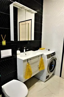 a bathroom with a washing machine under a sink at Nauji apartamentai su kiemeliu in Kaunas