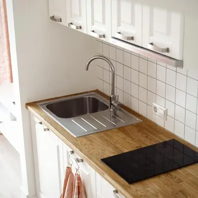 a kitchen with a sink and white cabinets at Domi Lini in Druskininkai