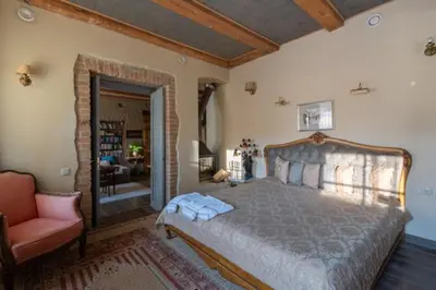a bedroom with a large bed and a chair at Uzupis Angel 3 bedroom Apartment in Vilnius