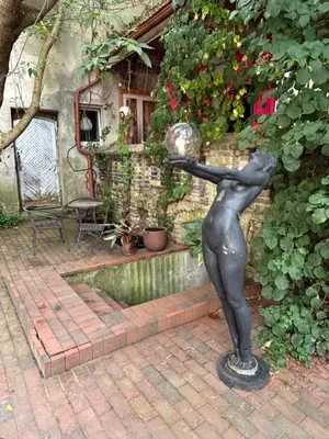 a statue of a woman holding a ball in a garden at Uzupis Angel 3 bedroom Apartment in Vilnius