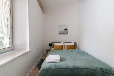 a bedroom with a green bed in a white room at New and modern apartment in Old Town by URBAN RENT in Vilnius