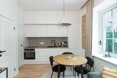 a kitchen with a wooden table and black chairs at New and modern apartment in Old Town by URBAN RENT in Vilnius