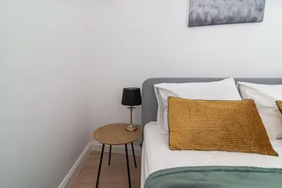 a bed with white pillows and a side table at New and modern apartment in Old Town by URBAN RENT in Vilnius