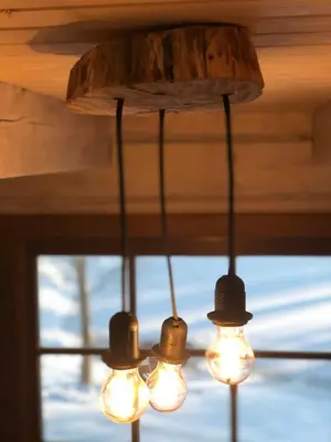 a chandelier with lights hanging from a ceiling at Liepų pirtis in Smailiai