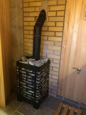 a black stove sitting next to a brick wall at Liepų pirtis in Smailiai