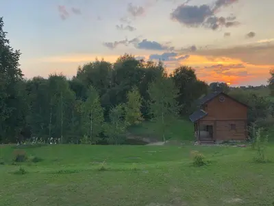 a small house in a field with a sunset in the background at Liepų pirtis in Smailiai