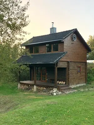 a large wooden house with a roof on a field at Liepų pirtis in Smailiai