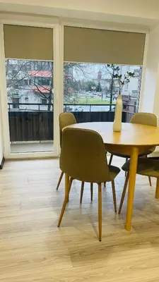 a dining room with a table and chairs and windows at S&T&A&R apartamentai in Panevėžys