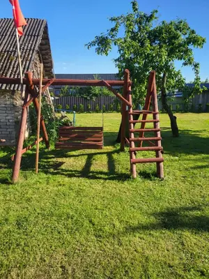 a wooden swing set in the yard of a house at Šimtametis namelis in Anykščiai
