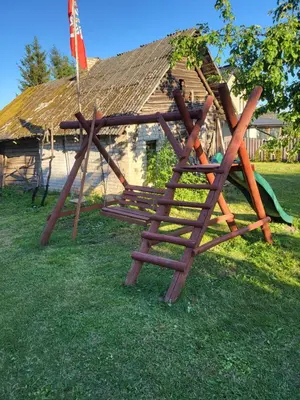 a wooden swing set in front of a house at Šimtametis namelis in Anykščiai
