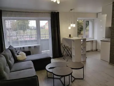 a living room with a couch and tables and a kitchen at Central cozy apartment in Kėdainiai