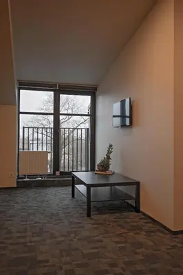 a living room with a table and a large window at LOFT INN Vilnius in Vilnius