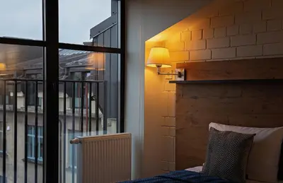 a room with a window and a bed and a lamp at LOFT INN Vilnius in Vilnius
