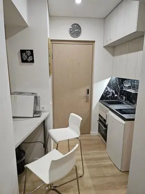a kitchen with two white chairs and a door at Kauno Apartamentai su balkonu in Kaunas