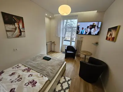 a bedroom with a bed and a tv on the wall at Kauno Apartamentai su balkonu in Kaunas