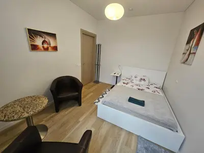 a bedroom with a bed and a chair and a table at Kauno Apartamentai su balkonu in Kaunas