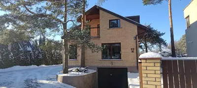 a brick house with a garage in the snow at Radikiai House in Smiltynai